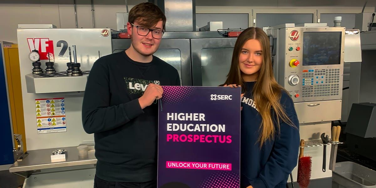 David O’Neill, from Newtownards, and Ellen Hutton, from Bangor, are completing the HND in Engineering at Bangor Campus  pictured in workshop with oversized Higher Education Prospectush p